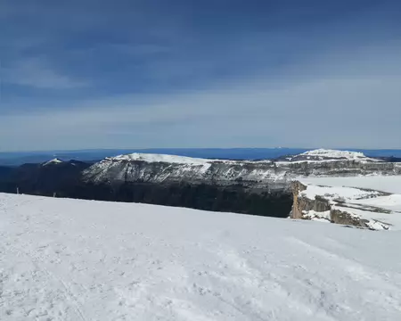 2026-02-22-11h58m05 Vue sur le plateau d'Ambel, le Roc de Toulau et vers les monts d'Ardèche enneigés (à environ 85km) depuis le Puy de la Gagère (1651m).